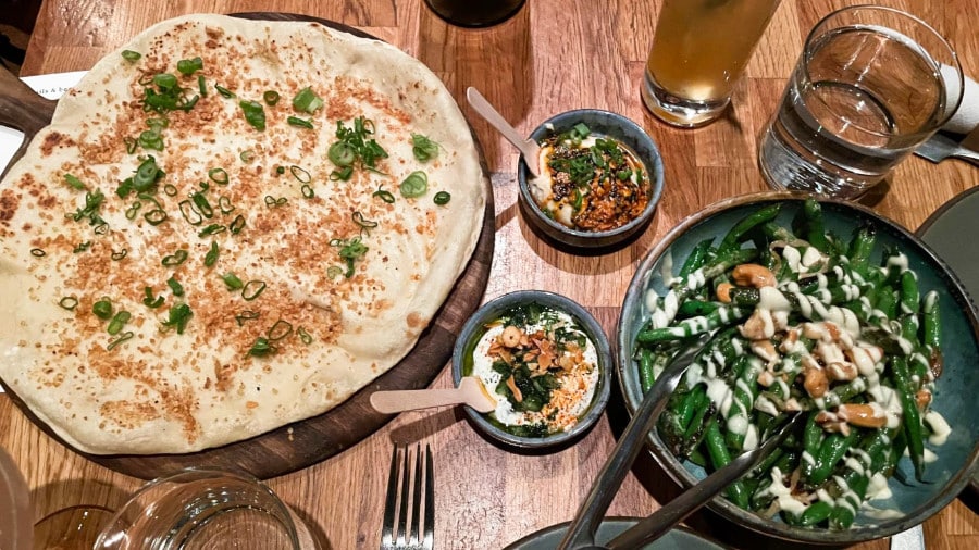 A food starter of Naan and dip, and sauteed green beans of Girl and the Goat