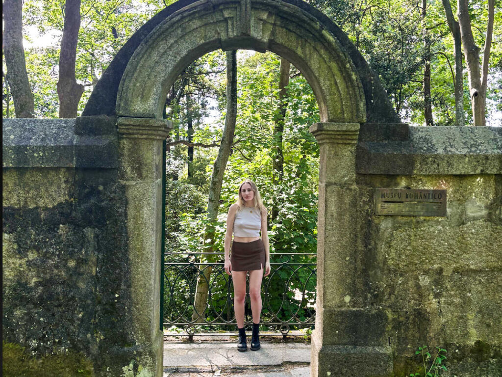The author Sky Ariella, standing under the  archway at a park in Porto