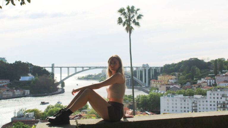 The author Sky Ariella, posing for a photo with an overlooking view in Porto