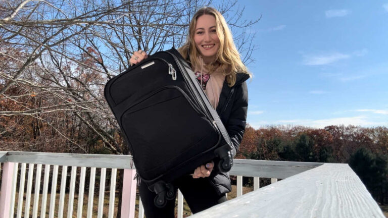 The author Sky Ariella holding her luggage bag at the balcony