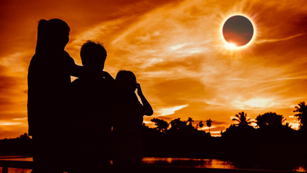 A silhouette of a family watching the solar eclipse on golden sky, solar eclipse travel destinations April 8 2024
