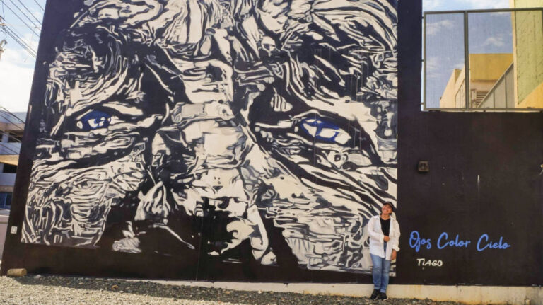 The author Vanessa Ramos smiling for a photo with street art on her background