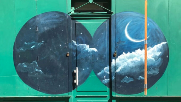A street art painting of a moon and clouds on a green door in Paris