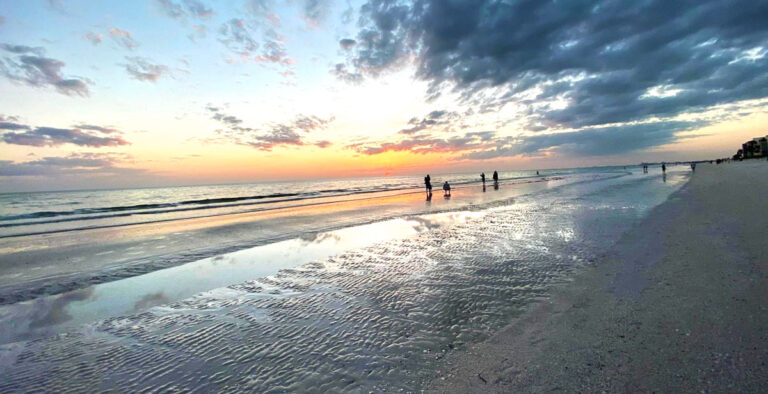 View of people by the beach and the colorful sky at sunset in Florida
