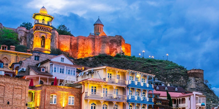 Illuminated view of the colorful buildings on the mountain cliffs at dusk