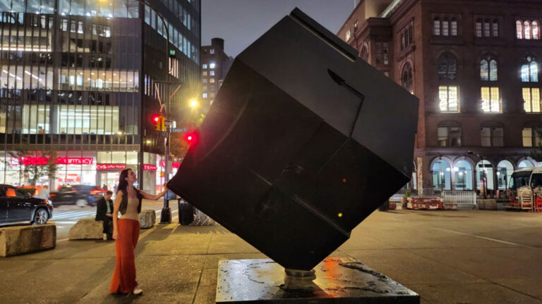 Author Niamh touches the Alamo sculpture in Astor Place at night