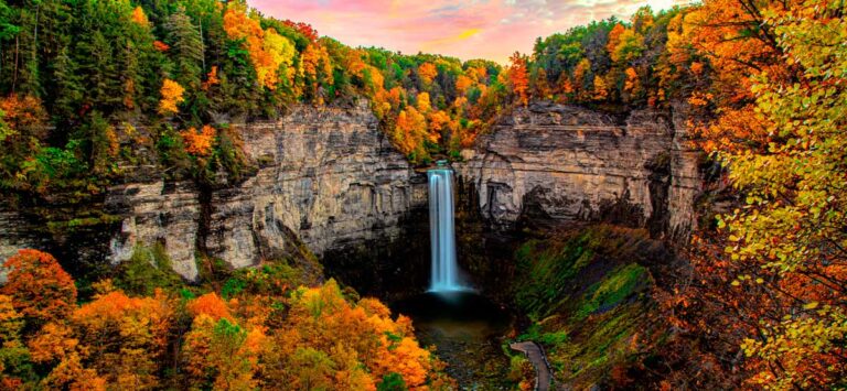 The Taughannock waterfalls under the colorful sky at sunset during fall season with brilliant orange and yellow changing color greenery