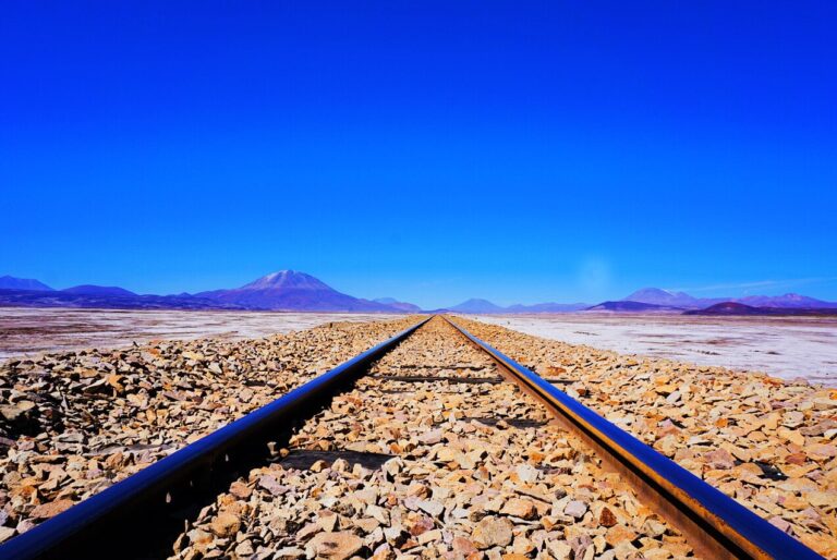 View of train tracks in Bolivian salt flats with mountains in the distance