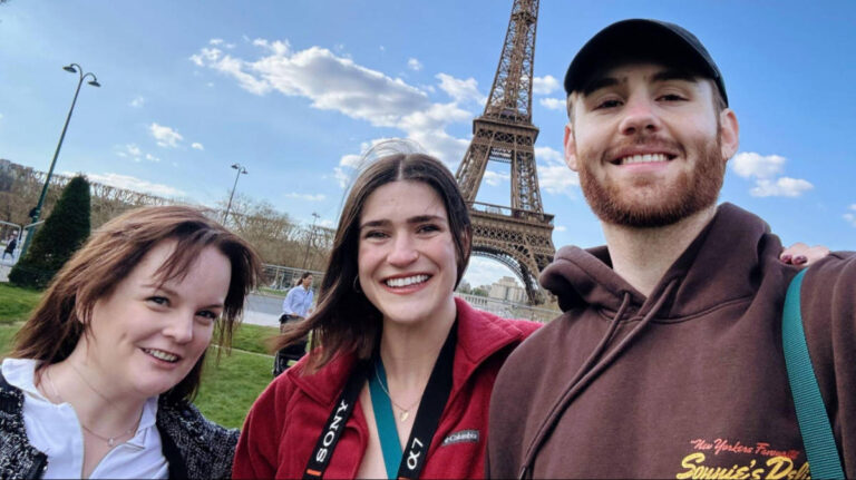 The author Rachel and Senior Writer Betty with a man smiling for a photo with the Eiffel Tower in the background