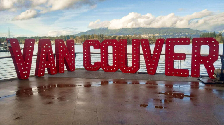 The signage of Vancouver with the the mountains and sea in the background