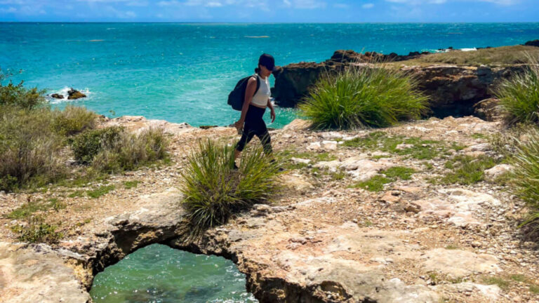 Travel Lemming Author Vanessa Ramos walking on rocky path over the ocean in Cabo Rojo