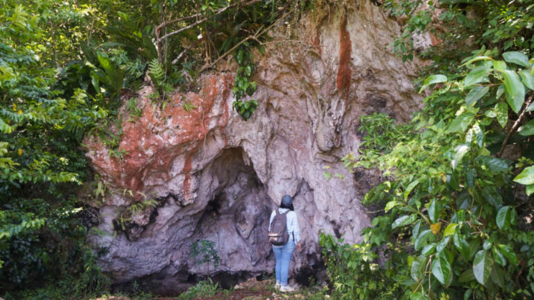 Author Vanessa looking at a limestone cave surrounded by lush greeneries