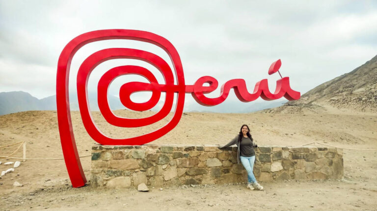 The author Vanessa posing for a photo in front of the signage of Peru