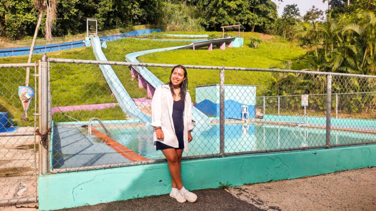 The author Vanessa Ramos, standing by the poolside of Monte Frio Waterpark with the slides in the background