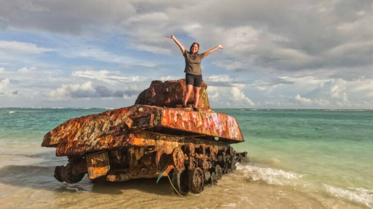 The author Vanessa standing confidently on an old tank at the beach
