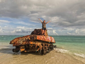 The author Vanessa standing on the rusted tank at Flamenco Beach