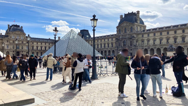 The crowd enjoying at the famous landmark in Louvre on a sunny afternoon