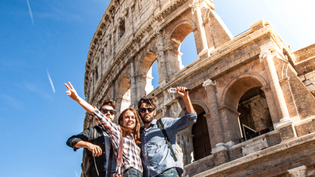 A group of tourists taking a photo in front of the Colosseum on a sunny day, why you cannot do Europe