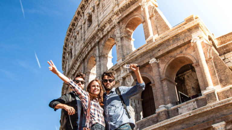 A group of tourists taking a photo in front of the Colosseum on a sunny day, why you cannot do Europe