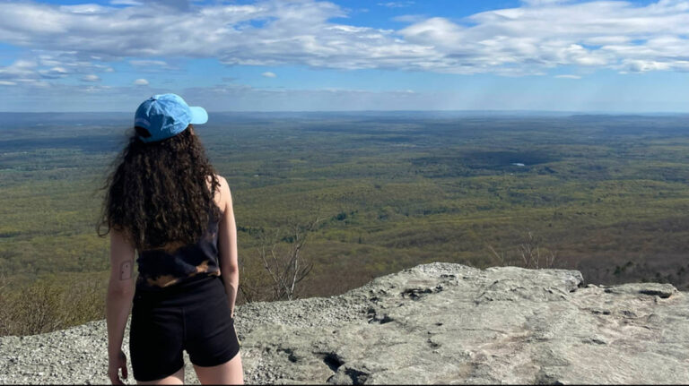A woman overlooking the scenic view of the landscape from the cliff