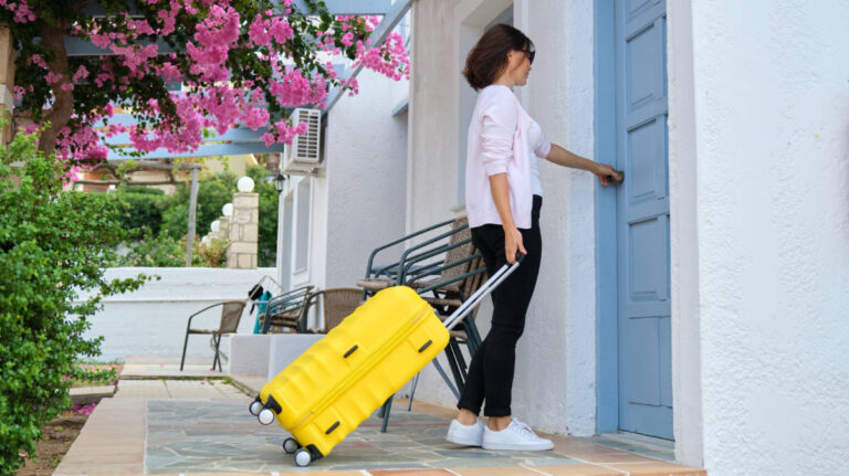 A woman with her yellow luggage entering her AirBnb