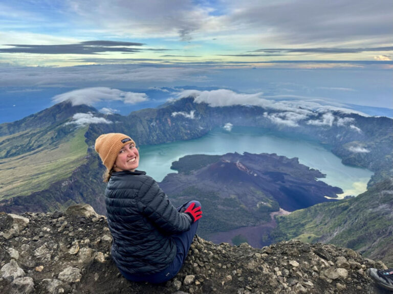 Writer Laura McFarland smiling brightly on the summit of Mount Rinjani